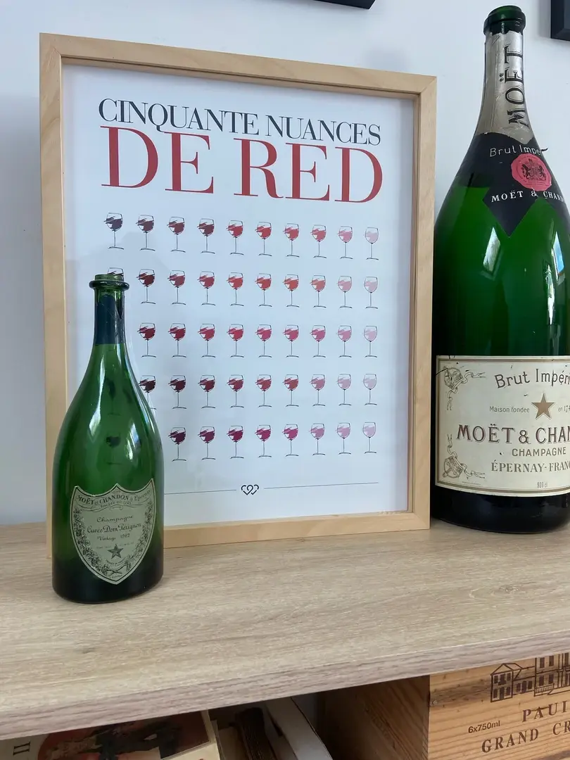 Cadre Eva rehaussée en bois clair sur une étagère en bois, affiche typographique et bouteilles de champagne