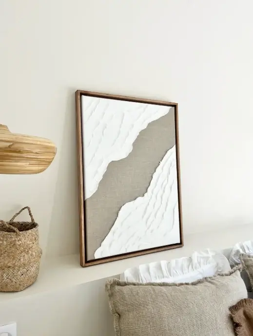 Cadre Marilyn autour d'une œuvre en relief blanche et lin, coussins et panier tressé
