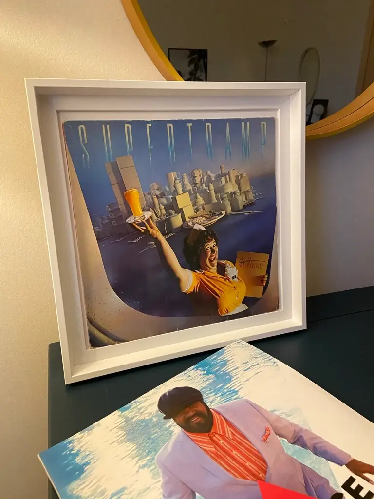 Cadre Scarlett blanc et profond encadrant une pochette de vinyle, près d'un miroir rond