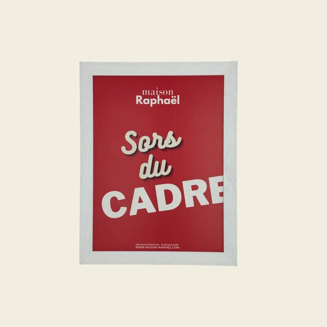 Cadre Gabrielle blanc laissant apparaître le grain du bois, vu de face avec une affiche rouge