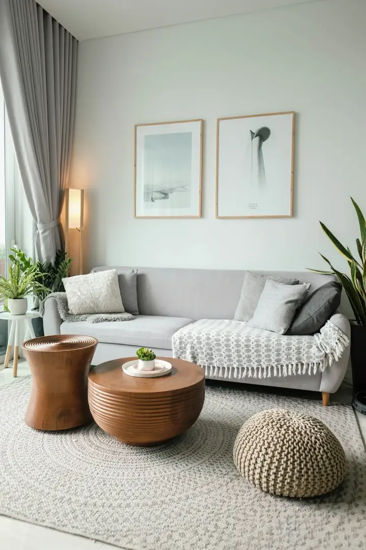 Salon avec canapé gris et tables rondes en bois, deux cadres en bois clair à photos minimalistes